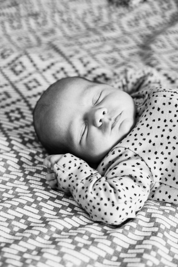 Newborn baby boy sleeping on a bed at a home photo session