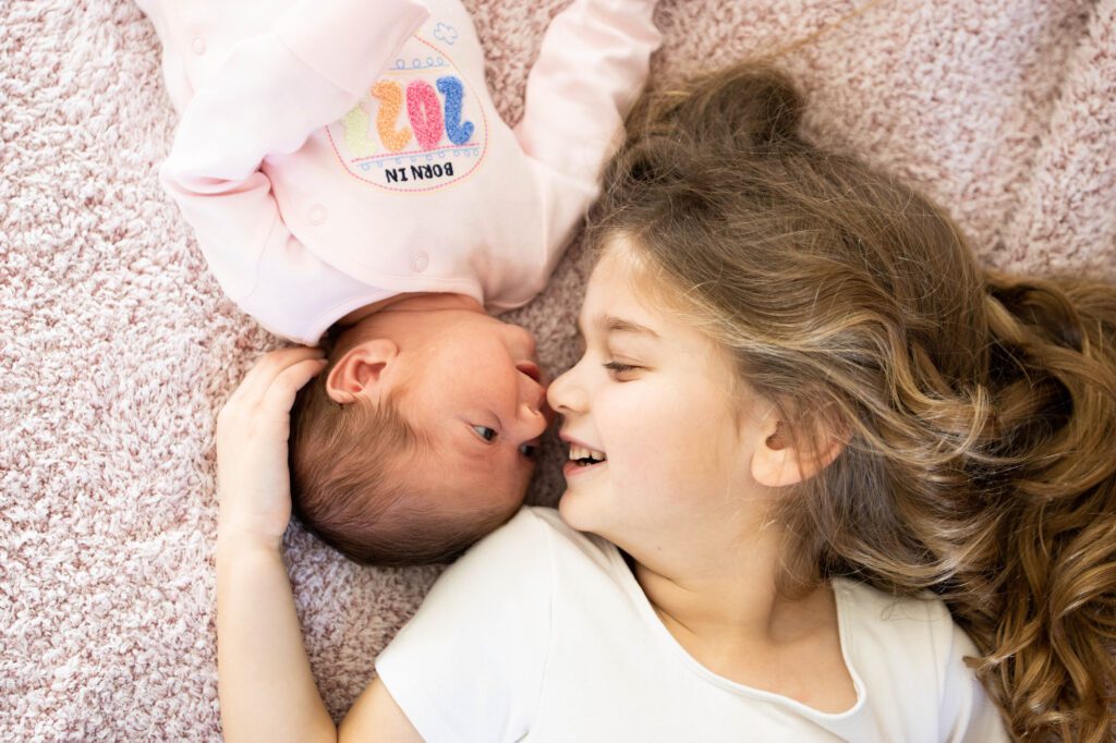 Girl and newborn baby sister touching noses at a home photo shoot, Leighton Buzzard, Bedfordshire