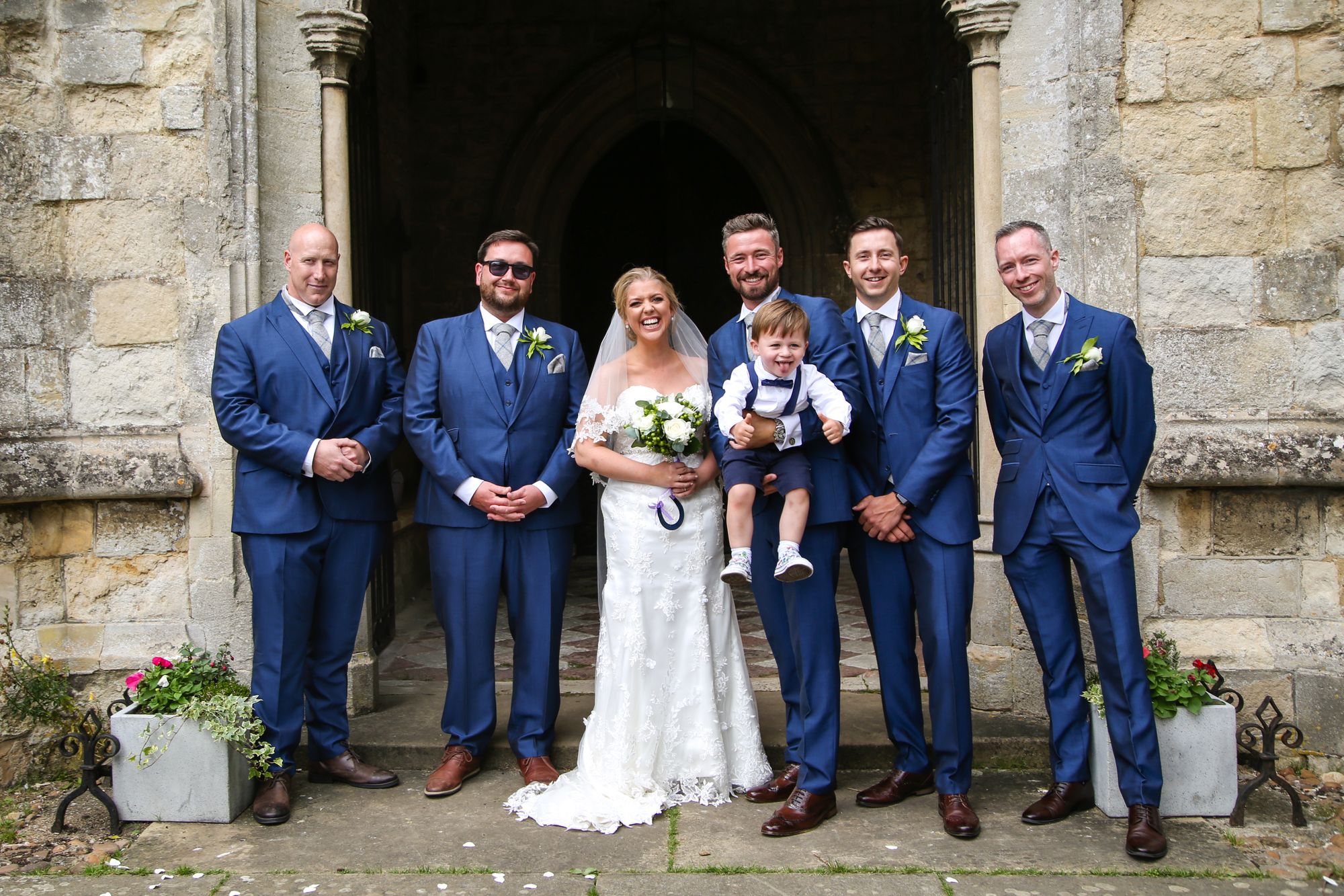 Photo of bride and groomsmen with page boy portrait outside wedding church by Tanya Aldcroft Photography