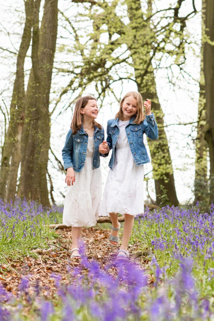 Sisters giggling at bluebell photo shoot near Tring, Hertfordshire by Aldcroft Photography